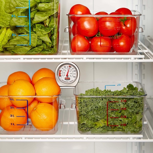 Rubbermaid thermometer in a refrigerator with lots of fresh fruits and vegetables in clear bins.