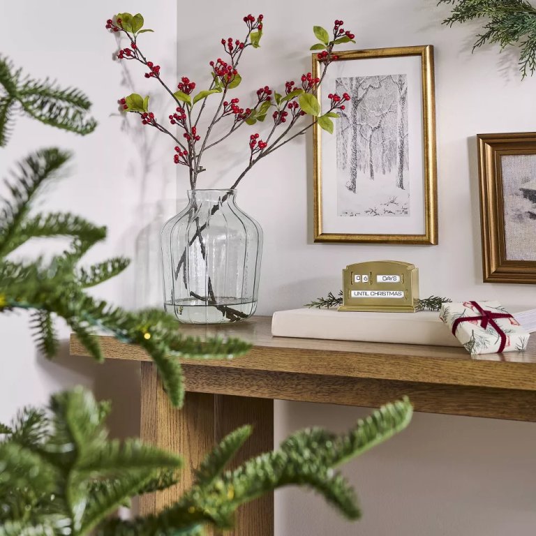 Faux stems with red berries on a table for holiday decor.