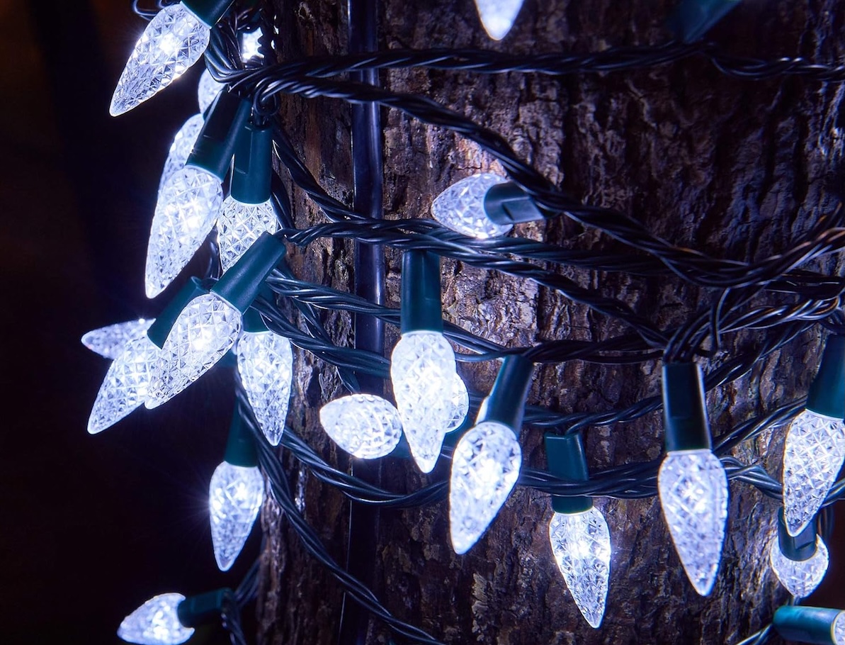 C6 Twinkle Star Christmas Lights in cool white wrapped around a tree.