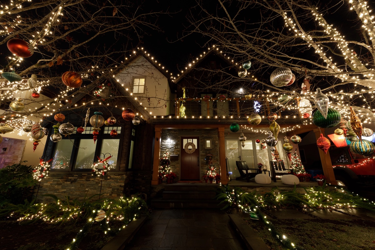 House at night illuminated by many different kinds of Christmas lights.