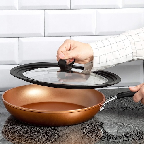 Person using Ecolution universal lid on a copper saute pan on a stovetop
