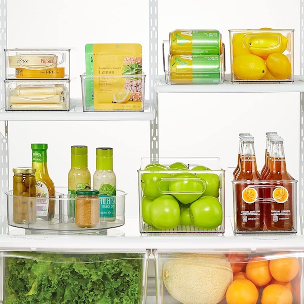 mDesign lazy Susan with condiments on it, inside a full fridge organized with baskets and bins.