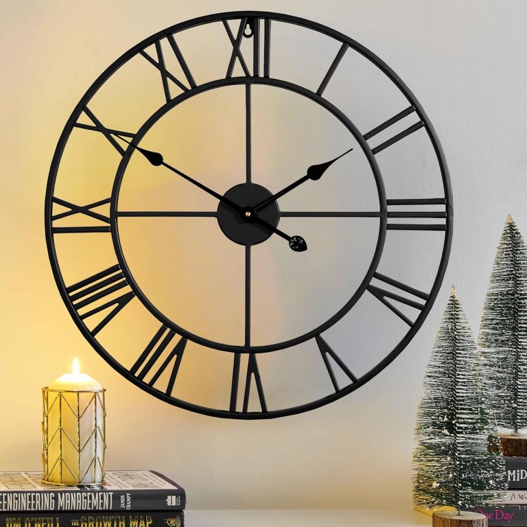 CLXEAST Silent 24 Inch Wall Clock hanging on a wall with books, candles, and holiday decor beneath