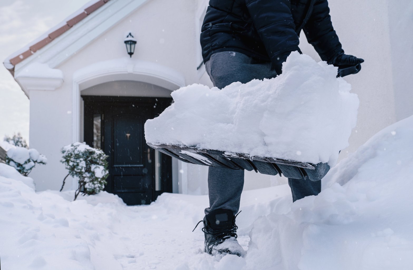 Man shoveling snow in front of house
