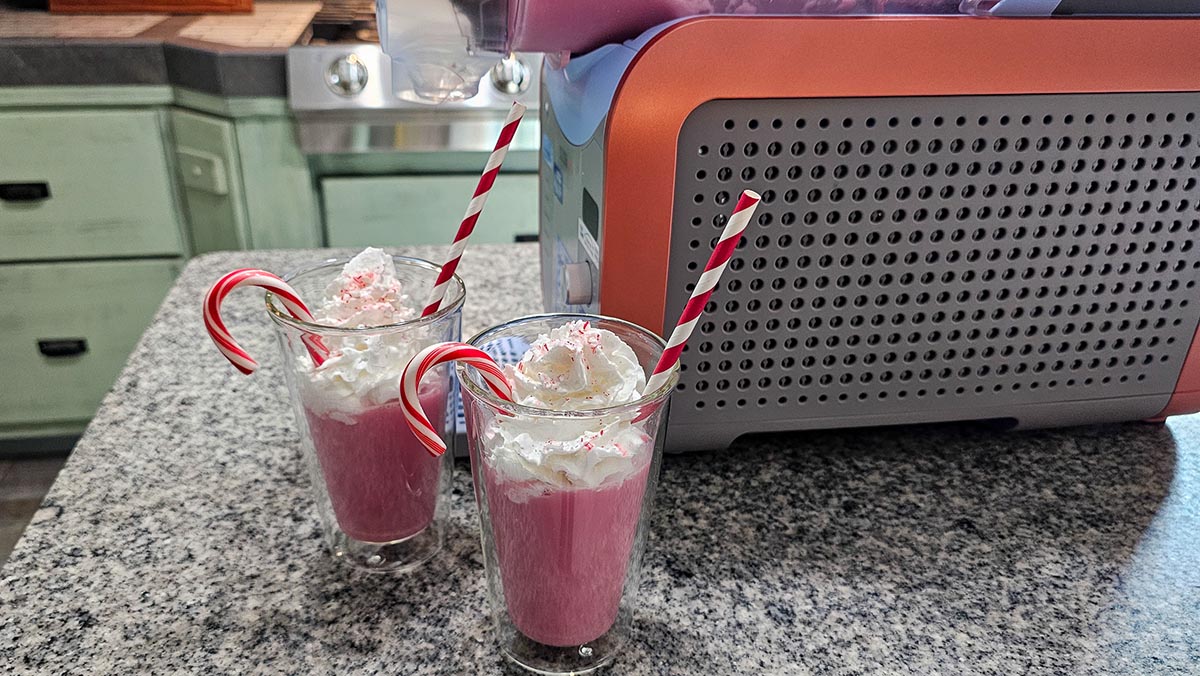 Two frozen drinks on a counter next to Ninja Slushi Max, ready to enjoy
