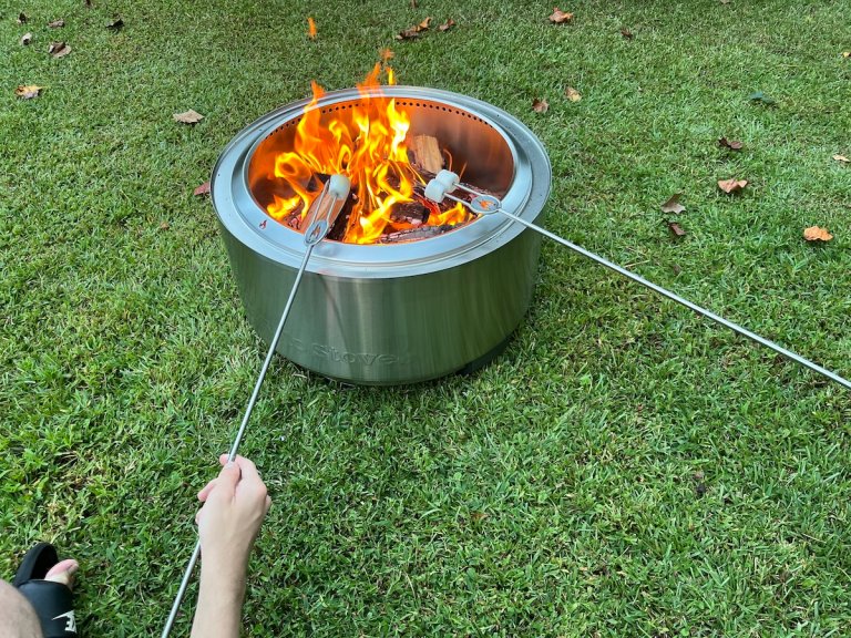 A man and companion roast marshmallows on skewers over the Solo Stove Summit 24