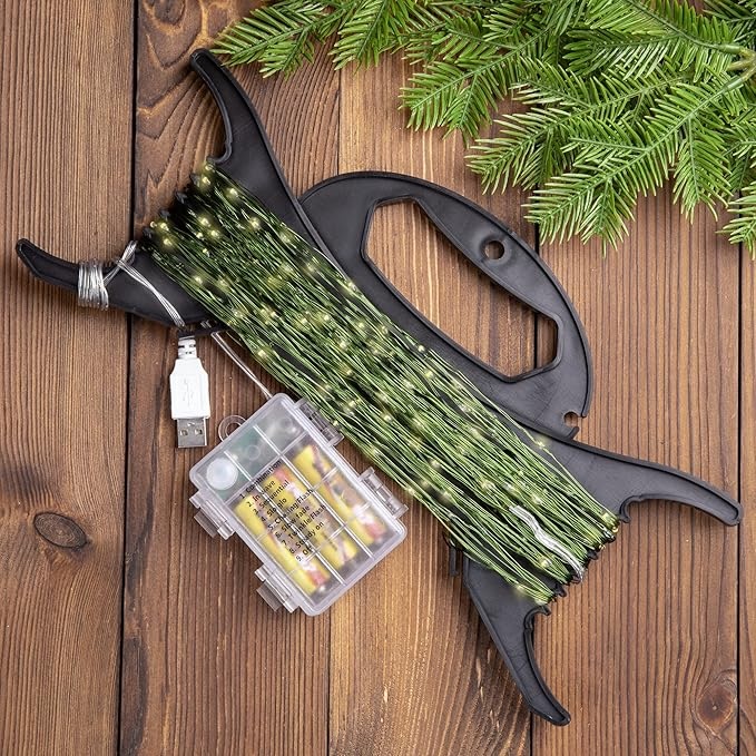 Codree Christmas lights organizer on a wood floor next to some tree greenery.