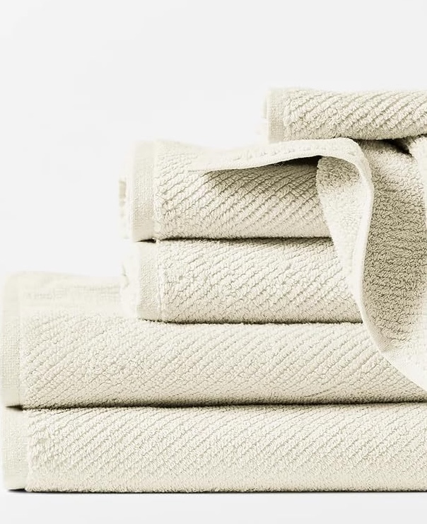 A stack of Coyuchi undyed towels, hand towels, and washcloths on a white background.