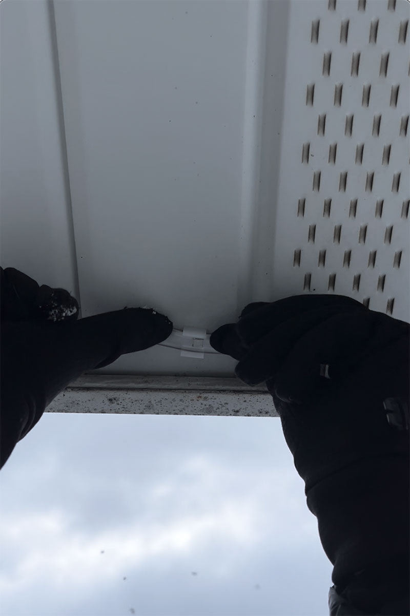 Editor Jenny Stanley installing Govee Outdoor Strip Lights in brackets on her house.