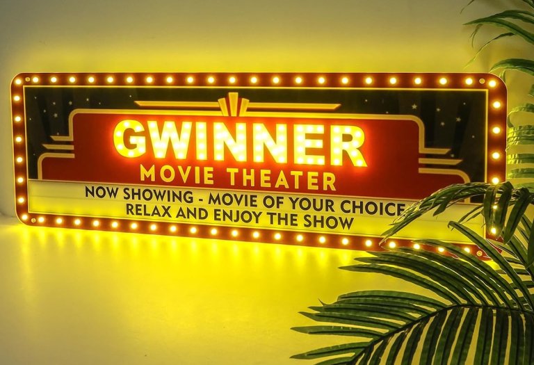 Minleoh custom movie marquee sign illuminated on a wall next to a plant.