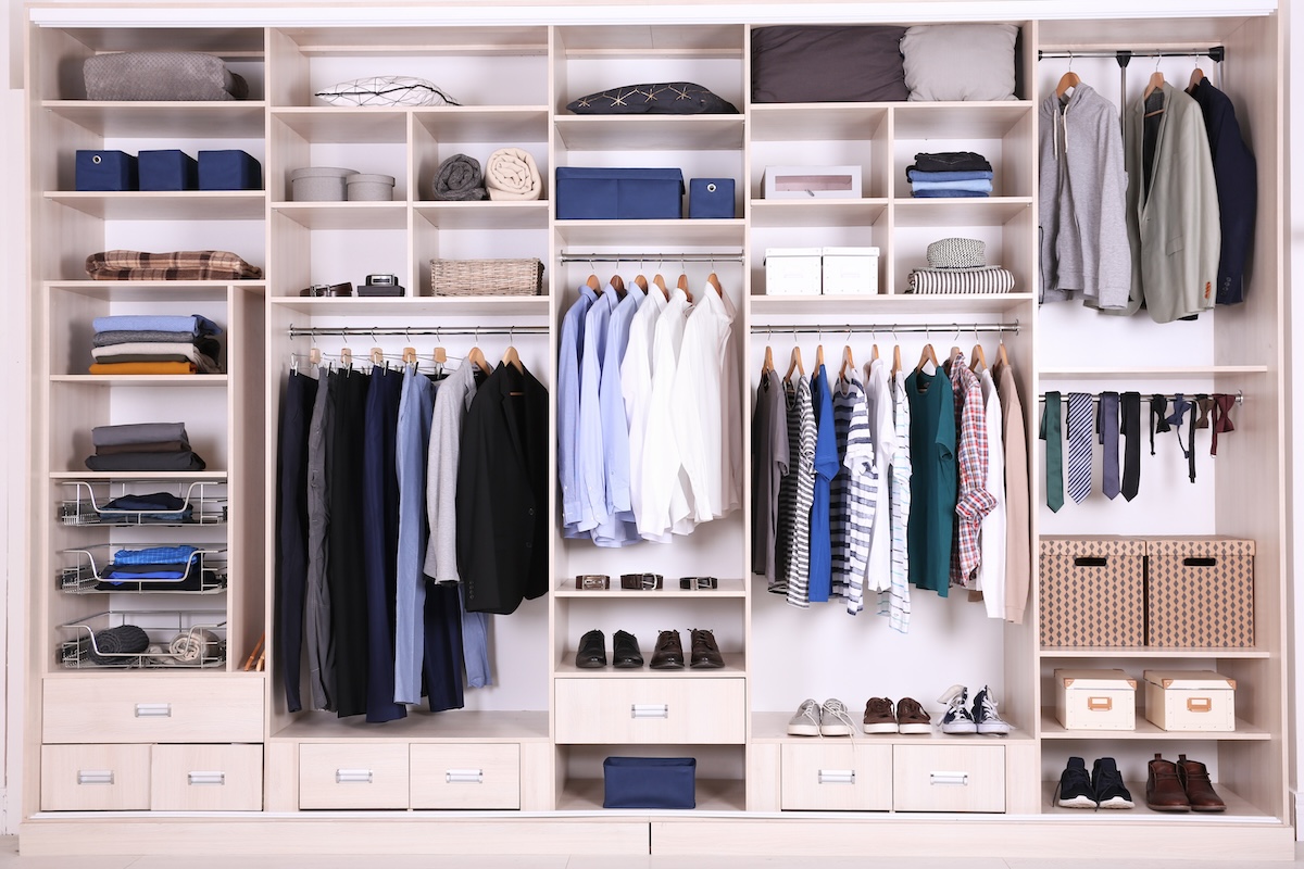 Large organized wall closet with sections for shirts, pants, ties, and items on shelves.