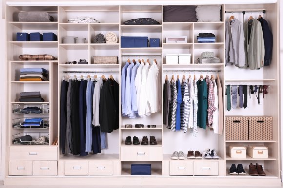 Large organized wall closet with sections for shirts, pants, ties, and items on shelves.