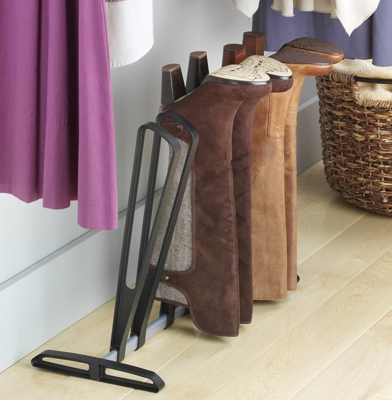 The Whitmor boot rack with boots on it, in a closet area with a purple curtain.