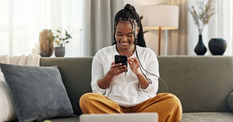 Happy woman and credit card with phone on sofa.