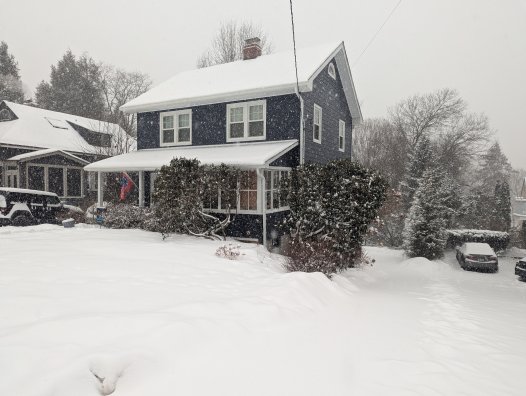 Navy blue house covered in snow from a big snowfall