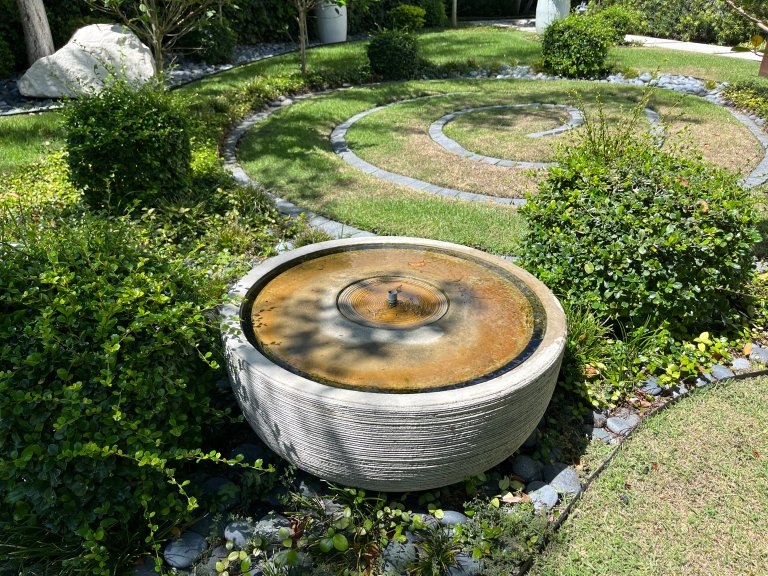 Gray bowl-shaped garden fountain in meditation garden.