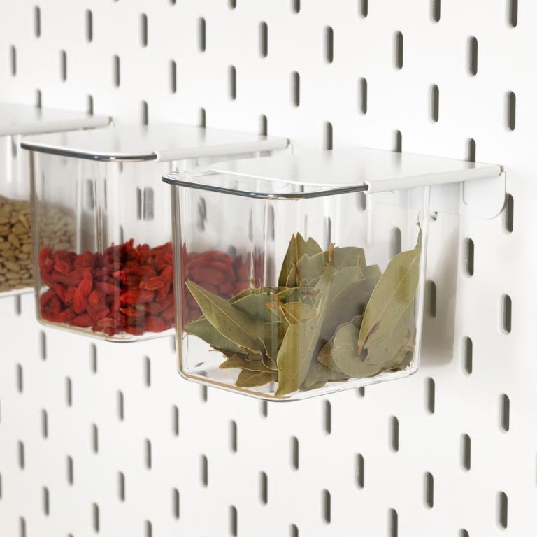 Ikea Skadis lidded containers storing spices on a kitchen pegboard
