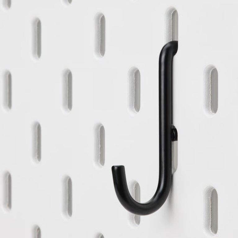 Ikea Skadis black hook hanging on a white pegboard