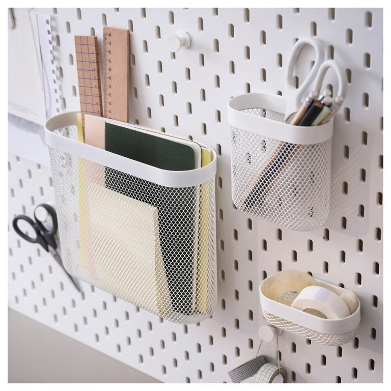 Ikea Skadis white basket trio hanging on a white pegboard to hold scissors, rulers, and paper