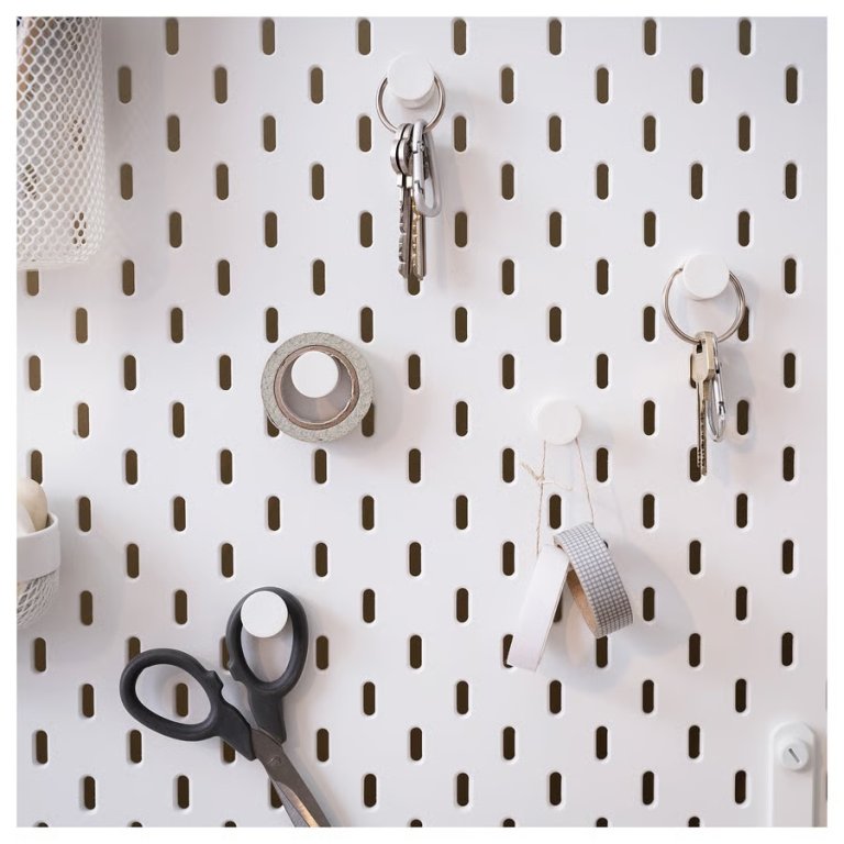 Ikea Skadis white round hooks used to hang scissors, tape, and keys on a white pegboard