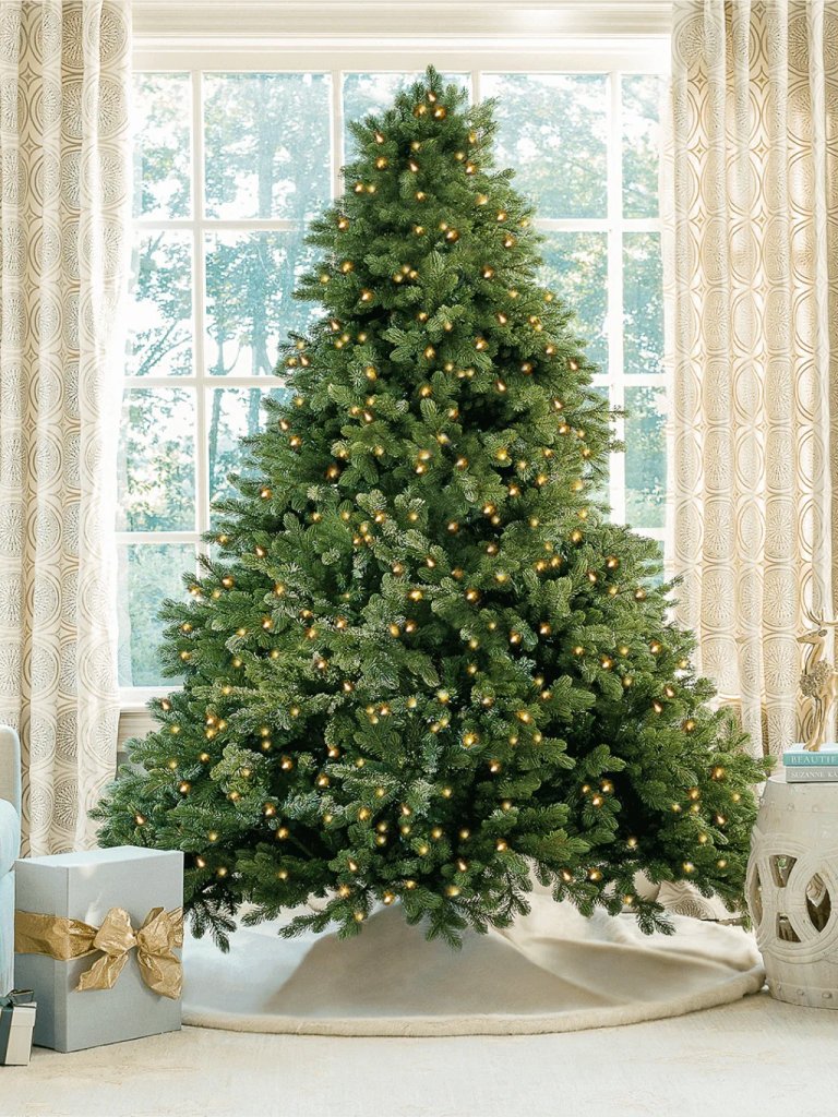 An artificial Christmas tree in front of a window in a home.