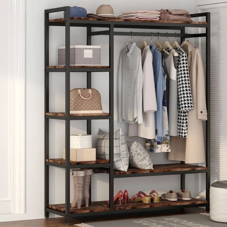 The Rebrilliant Olive Freestanding Closet System holding wardrobe items while set up along a white wall and window