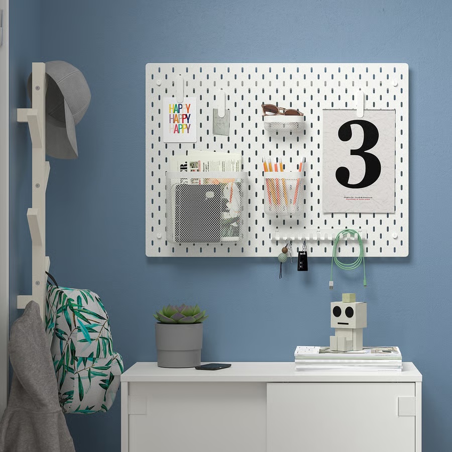 Ikea Skadis white pegboard used in an entryway to organize a drop zone, with spots for items like incoming mail, sunglasses, and more.