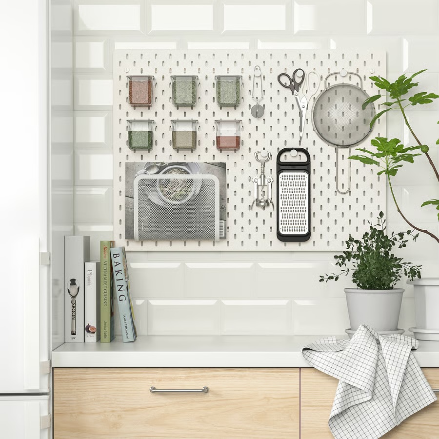 Ikea Skadis white pegboard in a kitchen to hang lightweight go-to tools: herbs, kitchen scissors, a wine stopper, a grater, and more.