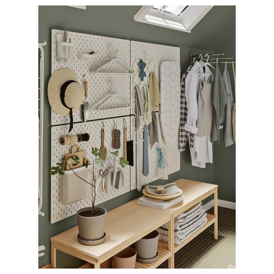 Four Ikea Skadis white pegboards used to hang laundry supplies in a combo mudroom-laundry room.