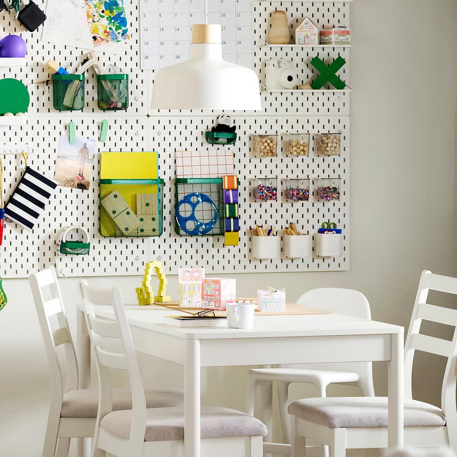 Four Ikea Skadis white pegboards used to create a wall of organization in a play room, where paper and art supplies can be stored