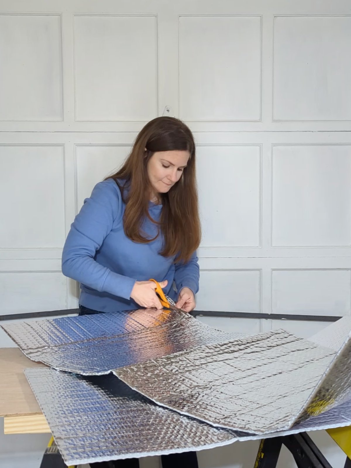 Woman trimming Reach Barrier garage door insulation panels to size