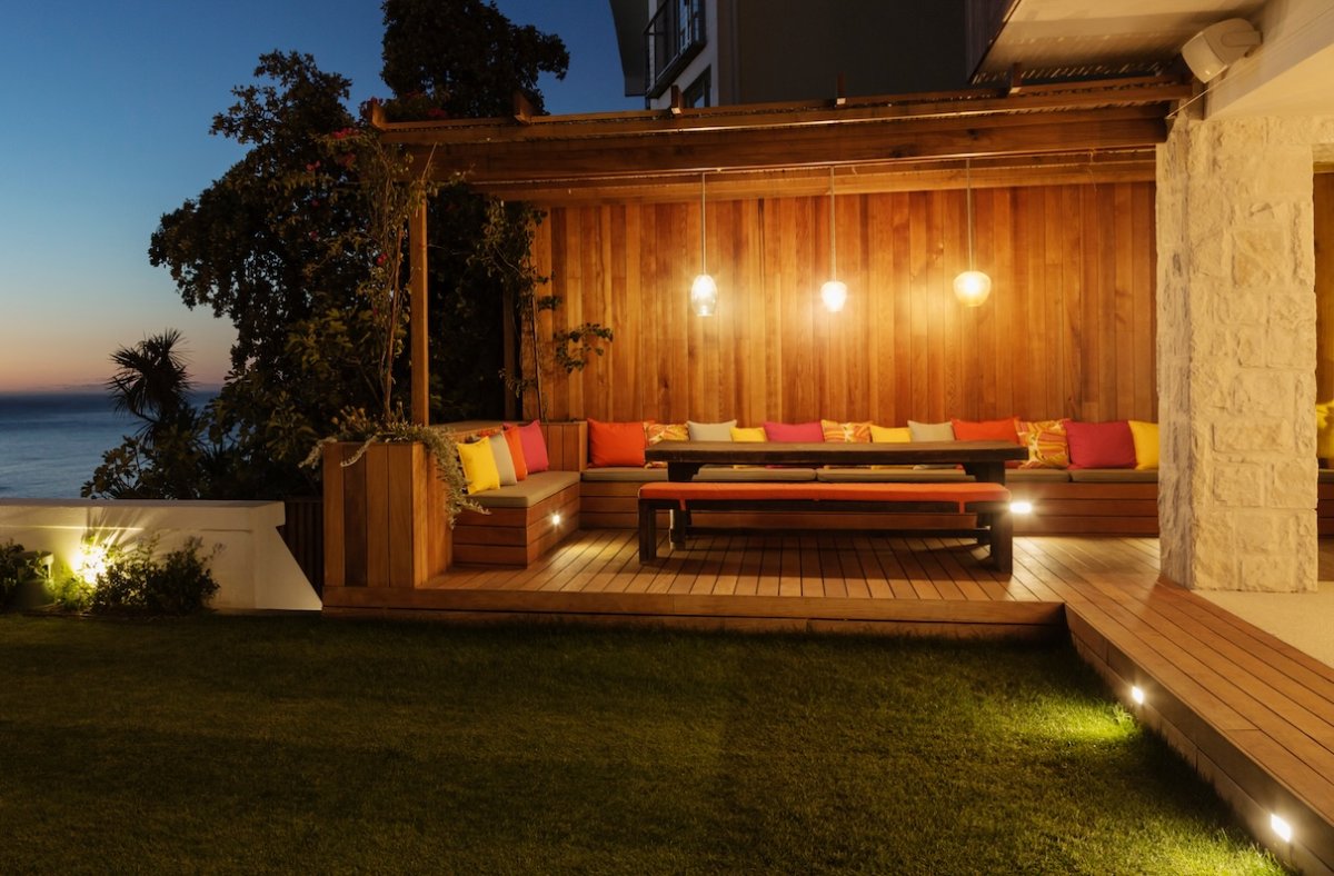 Enclosed patio with wood walls illuminated with sconce lights at night.