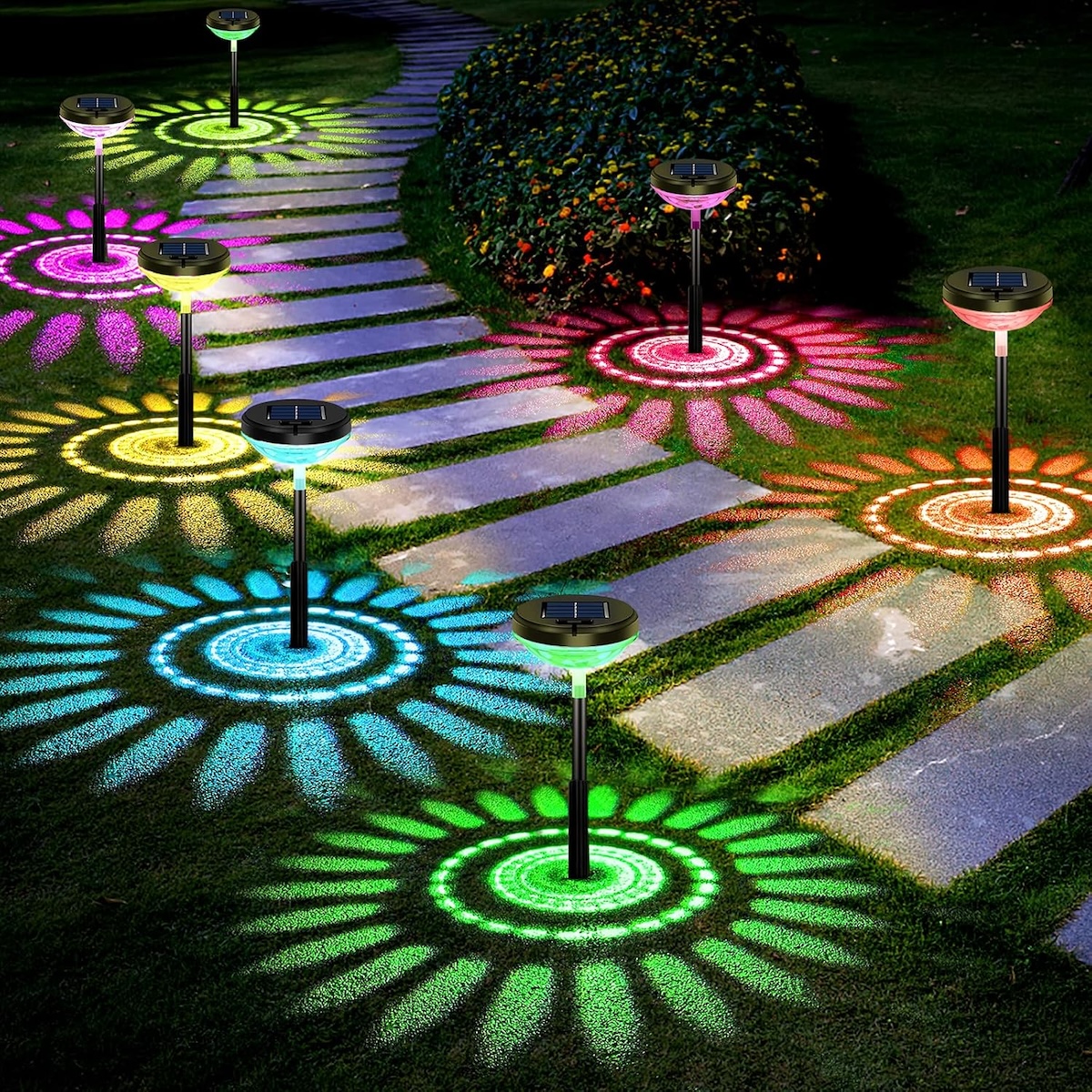A pathway with rainbow landscape lighting that casts a patterned shadow. 