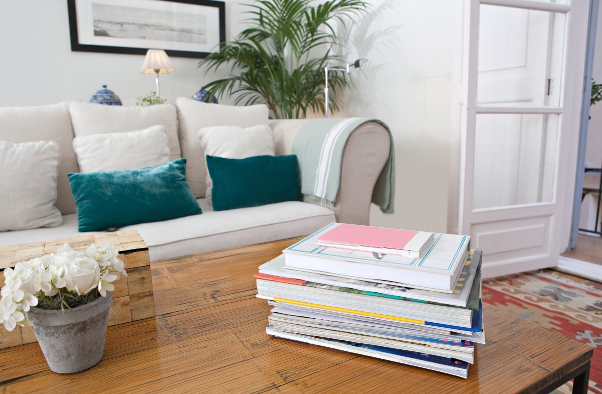 Living room with white sofa and green cushions with coffee table books sitting on a wood coffee table.