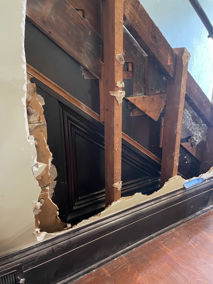 Hidden staircase trim revealed behind a wall.
