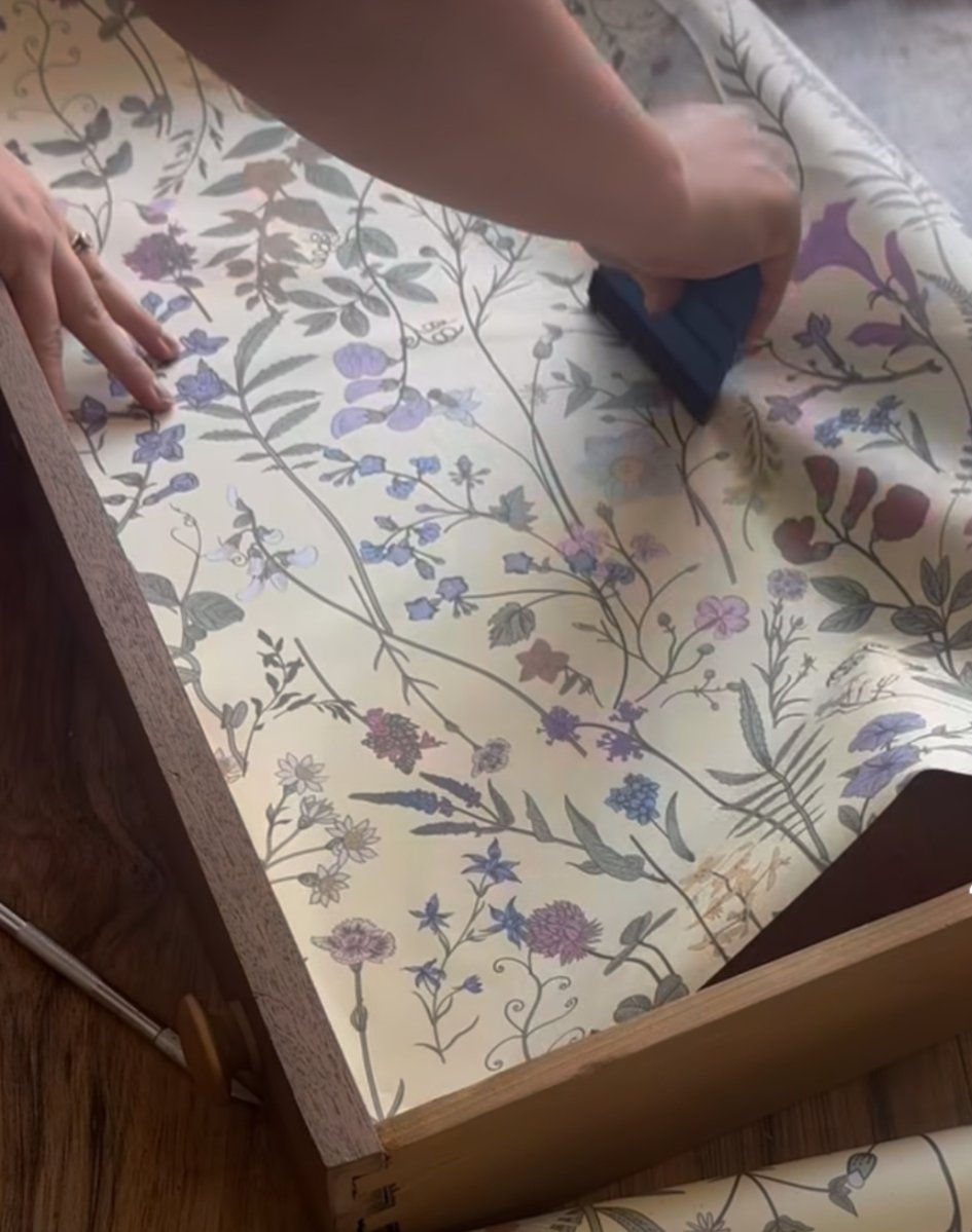 DIYer adding wallpaper to inside of dresser drawers.