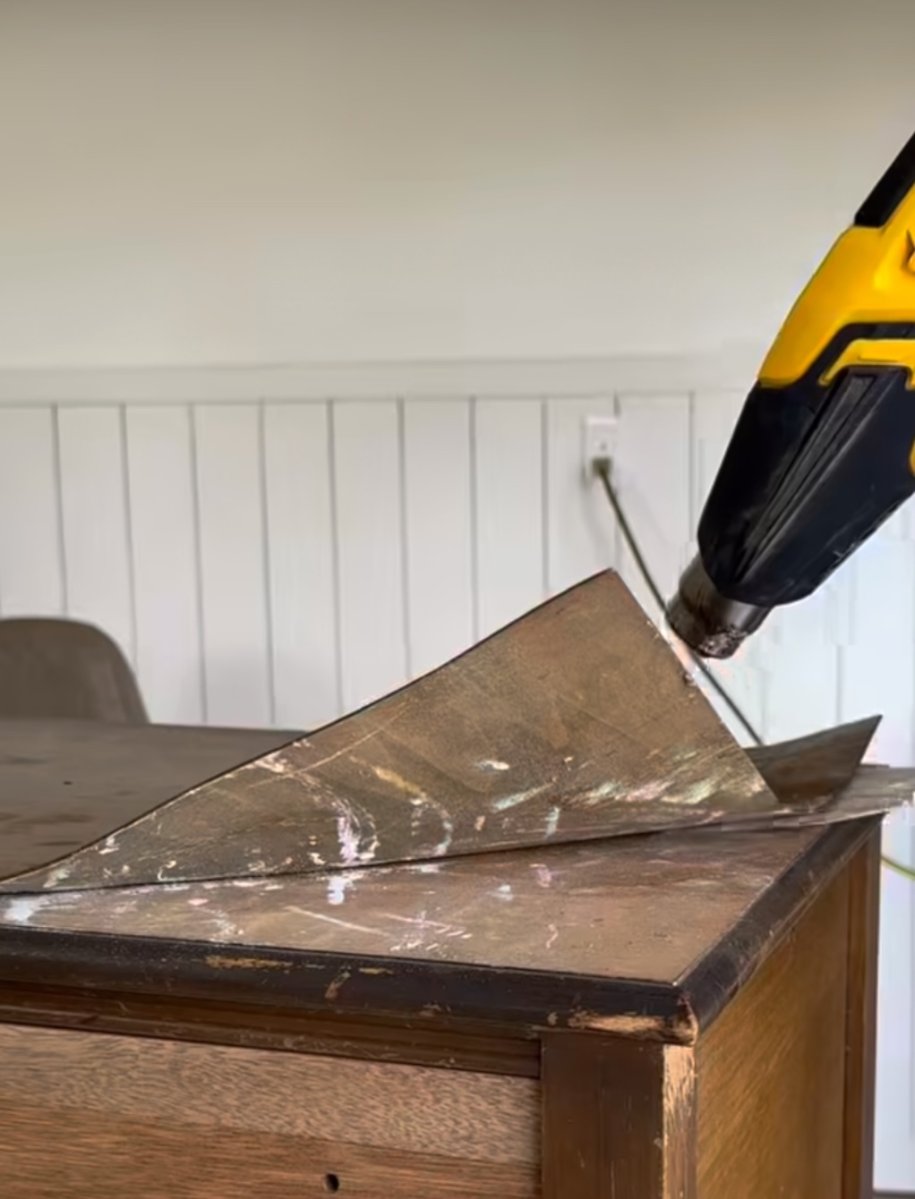 Removing old wood veneer using a heat gun.
