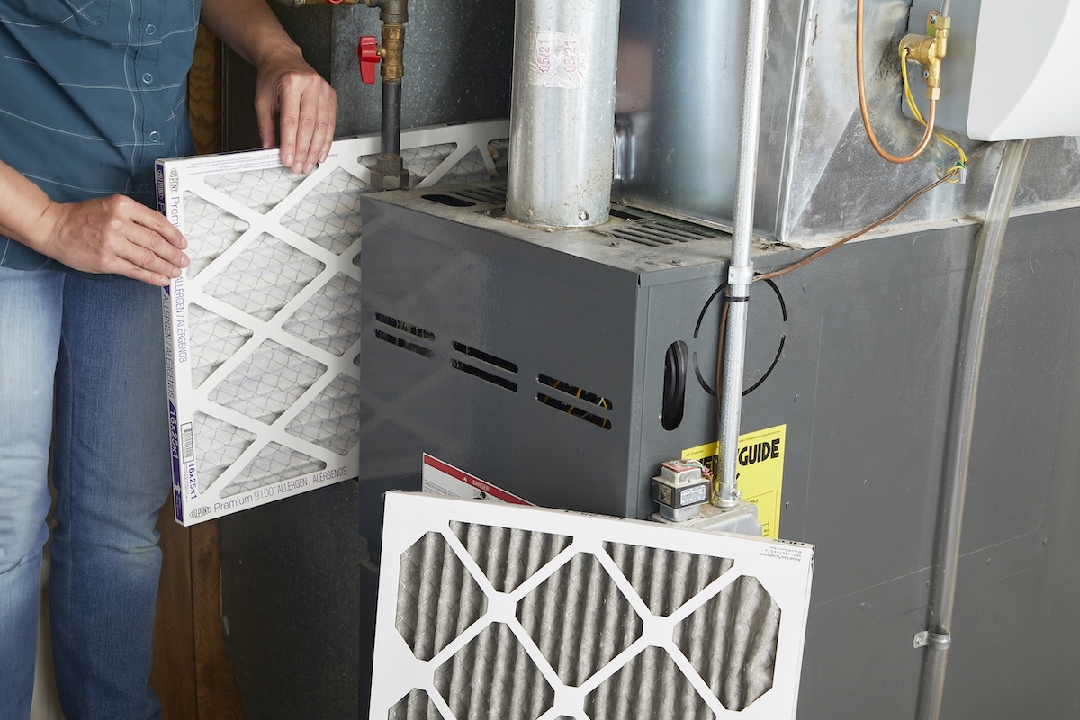 A person replacing an HVAC filter in a home furnace.