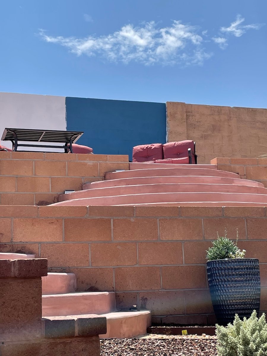A block fence in the process of being painted with primer and a bright blue color.