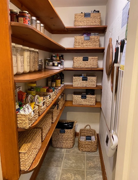 Organized kitchen pantry with baskets and plastic containers.