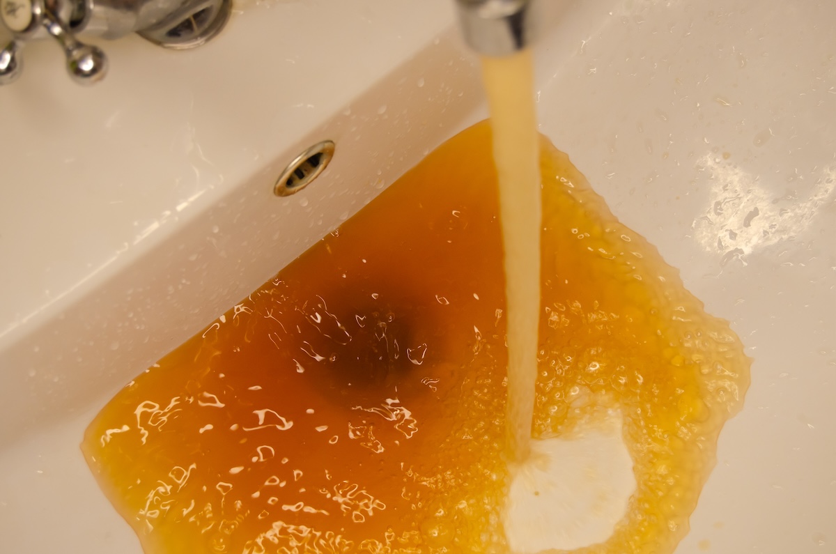 Rusty water flows out of a sink tap.