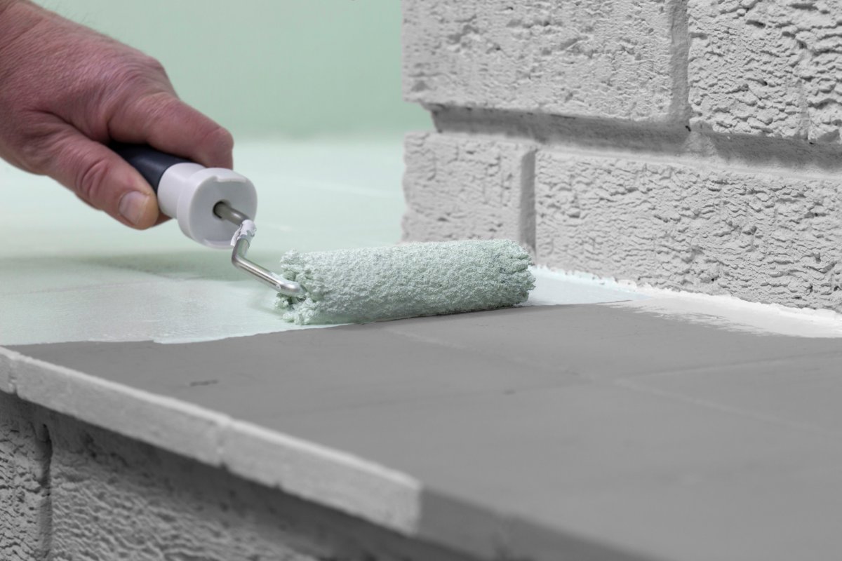 Man painting a fireplace with a paint roller.