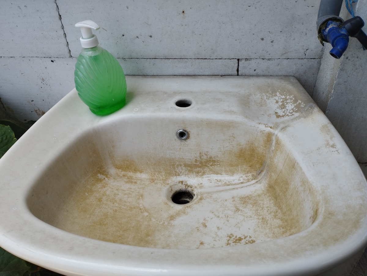 A white sink is covered in brown stains from old water.