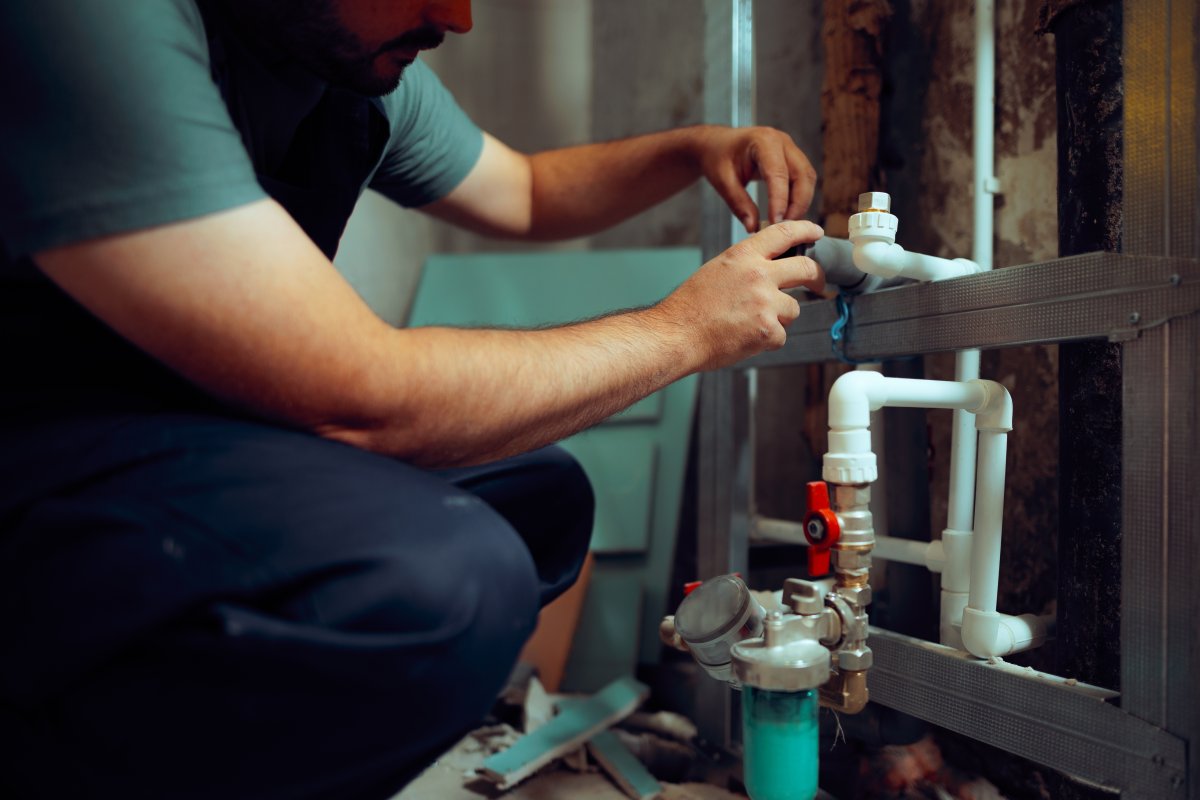 Plumber working on pipes in a bathroom being renovated.