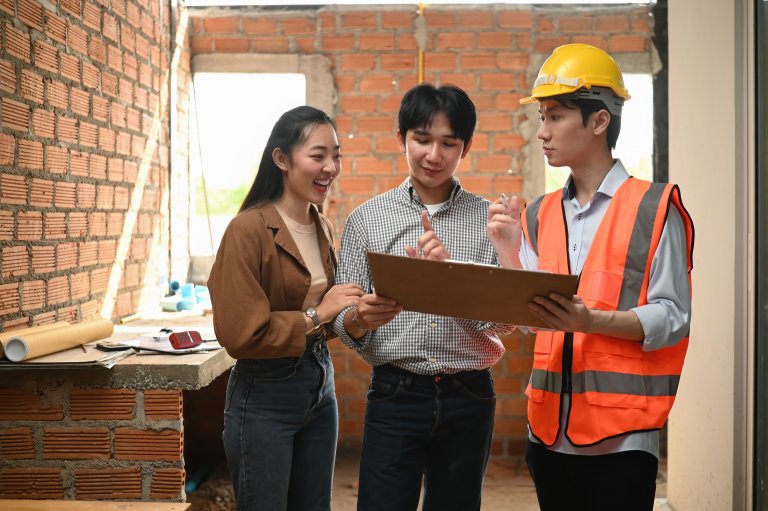 A couple meeting their site contractor to review architectural layout and home improvement updates for their renovation project.