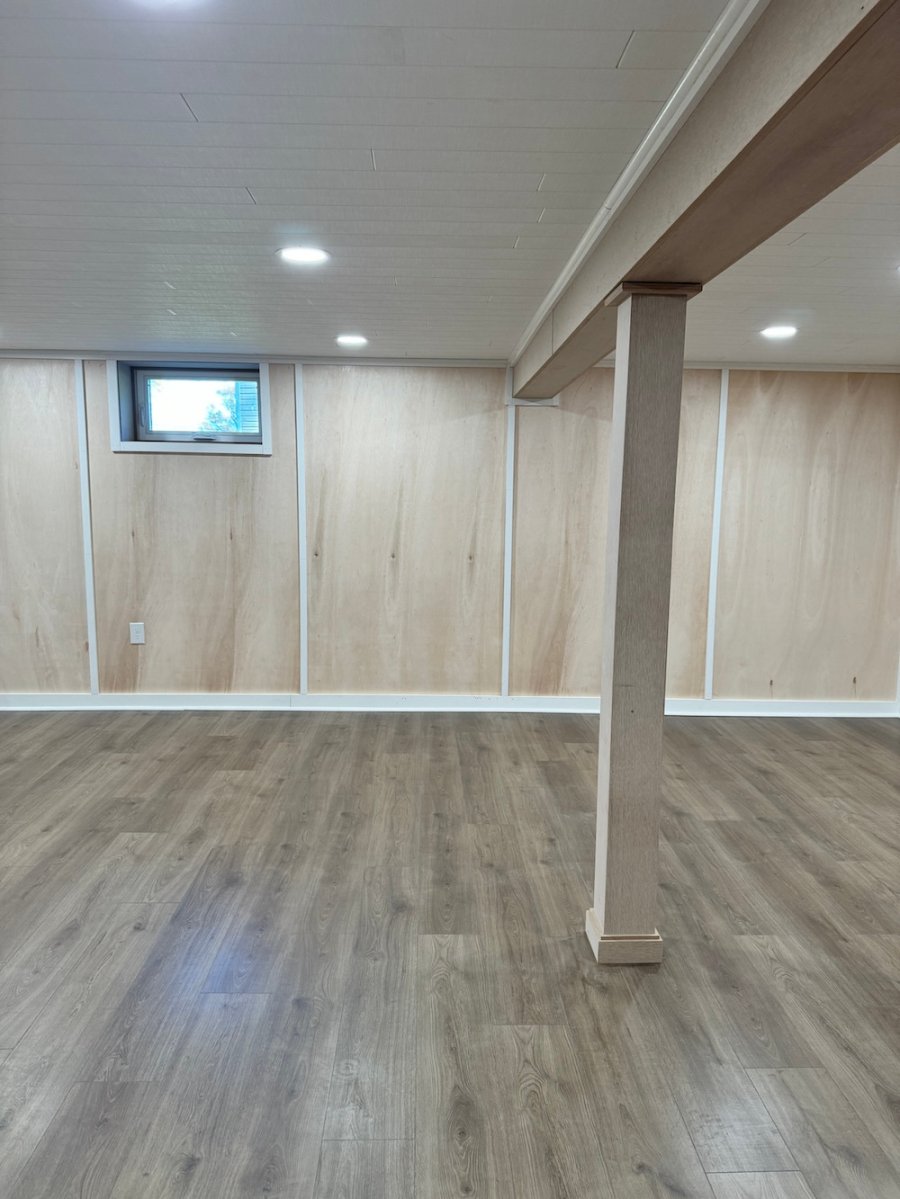 A completed finished basement with trimmed column and window.