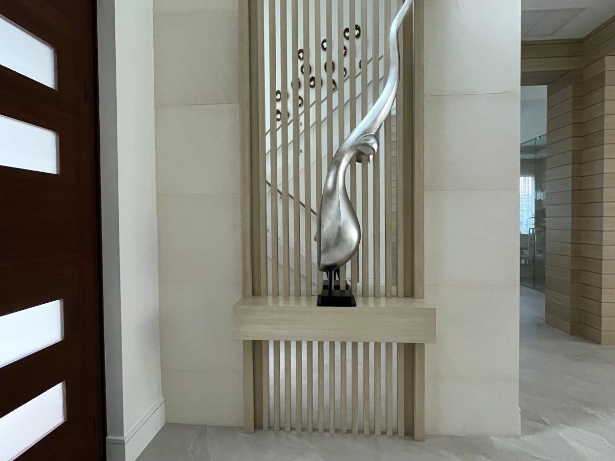 Floor-to-ceiling wood slat accent wall with silver sculpture. 