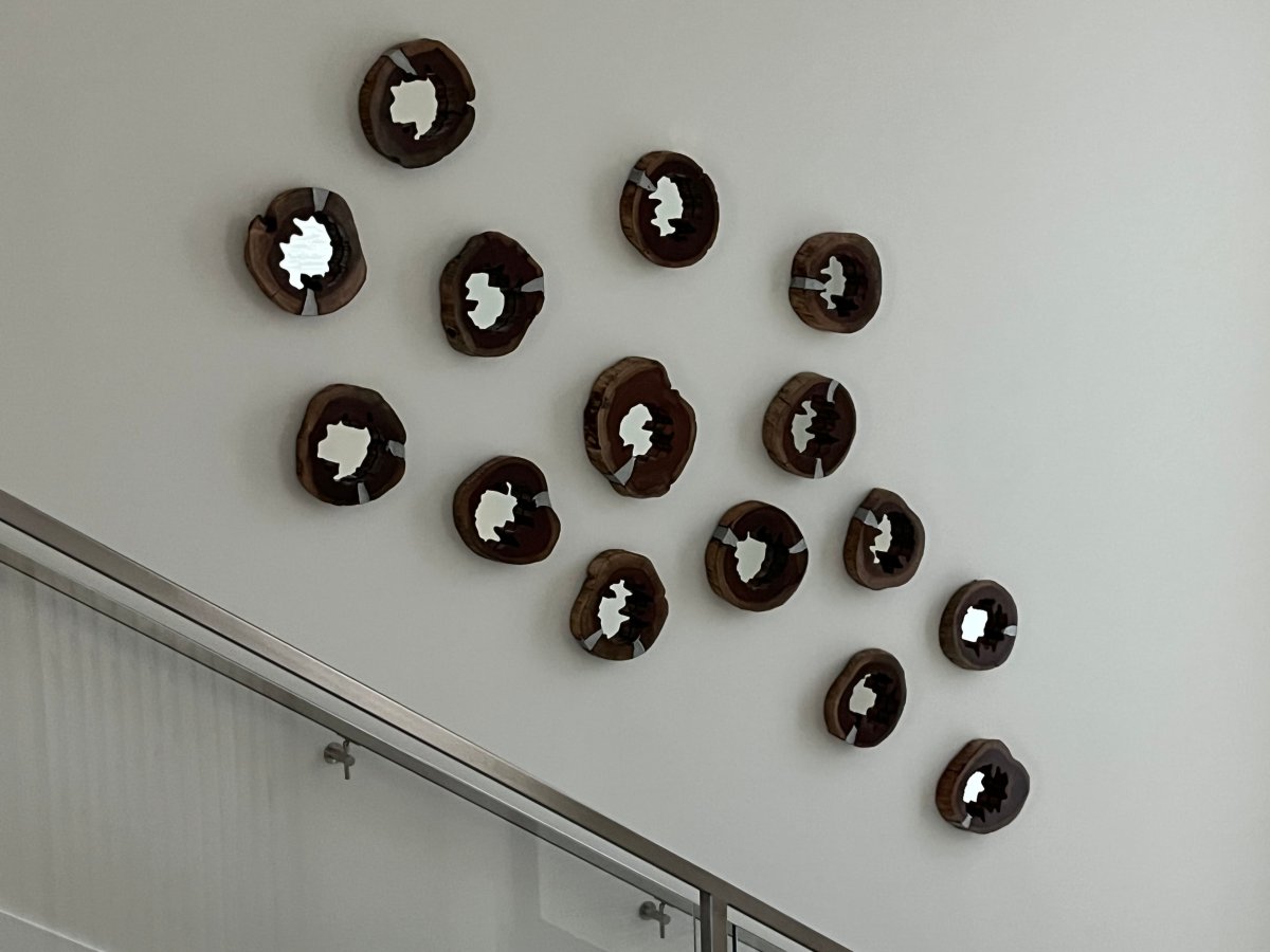 Multiple round mirrors with wood frames on the wall next to stairs.