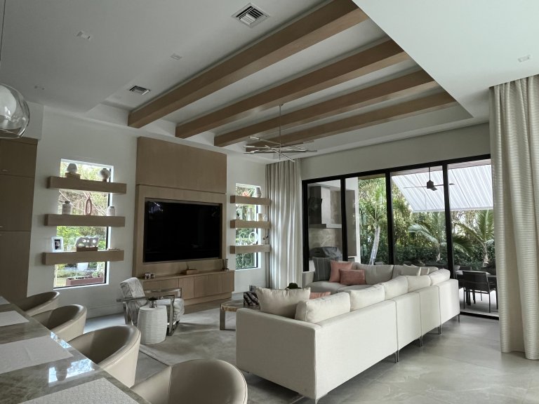 Modern family room with light wood ceiling beams and built-in for television and storage below.