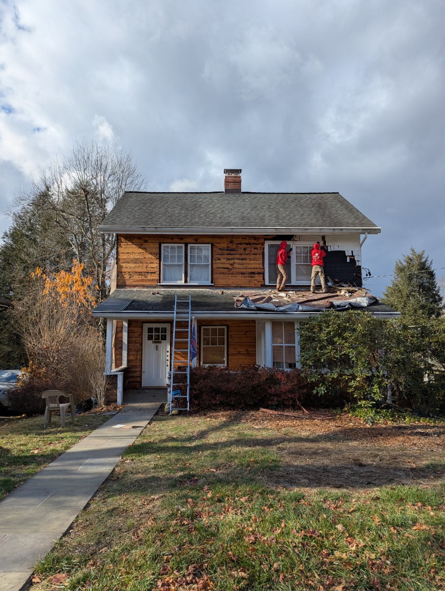 Replacing Siding in Early Winter, with Two Installation Professionals on the Second Floor of the House Removing Old Wood Siding